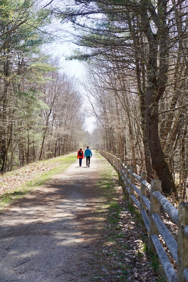 A couple walk along a secluded section of the Eastern Trail in the Kennebunk area. The trail passes through miles of quiet woodland bordered by streams and wetlands. Photo by Cindy Barks.