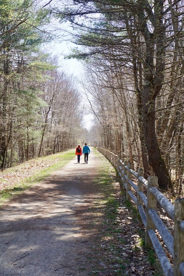 A couple walk along a secluded section of the Eastern Trail in the Kennebunk area. The trail passes through miles of quiet woodland bordered by streams and wetlands. Photo by Cindy Barks. A couple walk along a secluded section of the Eastern Trail in the Kennebunk area. The trail passes through miles of quiet woodland bordered by streams and wetlands. Photo by Cindy Barks.