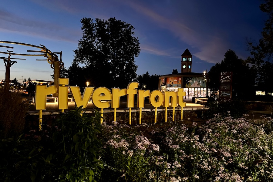 A nighttime view of the entrance to Spokane&rsquo;s Riverfront Park shows the Riverfront Rotary Fountain and the Great Northern Clocktower in the distance. Photo by Cindy Barks