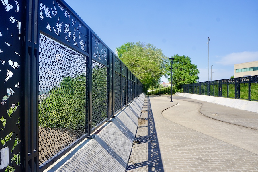 As the Riverfront Heritage Trail heads south from downtown Kansas City, it provides overpasses that allow pedestrians and cyclists to cross busy freeways. Near Mulkey Square Park, a pedestrian bridge across I-670 features a decorative walkway and ornamental iron fence depicting birds that inhabit the area. | Photo by Cindy Barks
