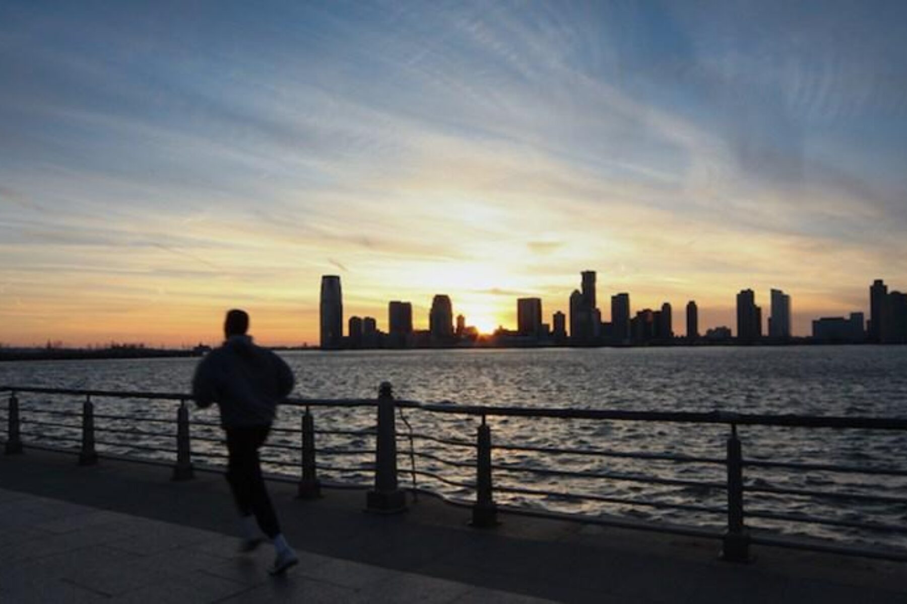 A jogger on the Hudson River Valley Greenway catches the last rays of the day’s light as the sun sets behind the New Jersey skyline. | Photo by Scott Stark