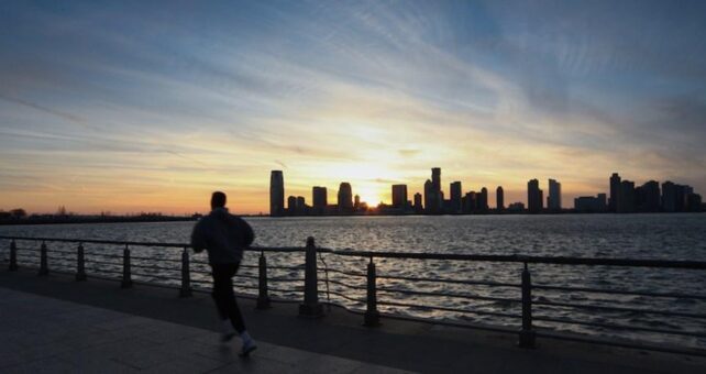 A jogger on the Hudson River Valley Greenway catches the last rays of the day’s light as the sun sets behind the New Jersey skyline. | Photo by Scott Stark