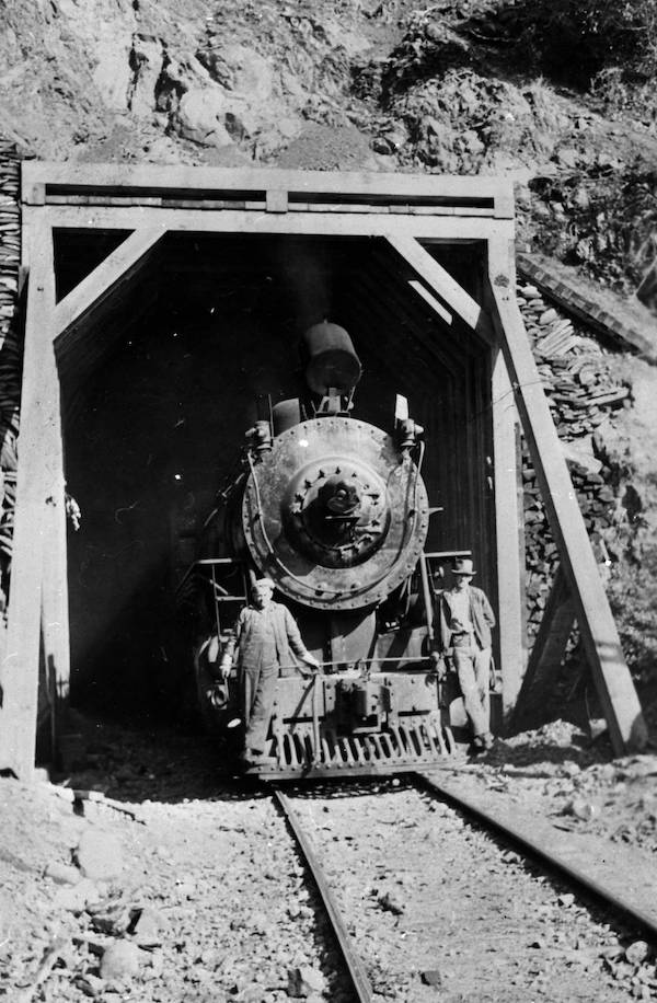 A train emerging into the north shore of Lake Crescent under a tunnel built by the Spruce Production Division | Photo courtesy Bert Kellogg Collection of the North Olympic Library System