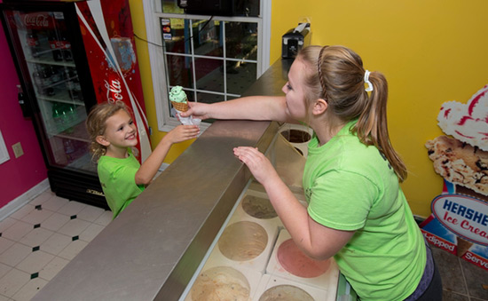 Alex Jones, a worker at In The Country, hands Emma Cree, visiting from South Carolina, a scoop of mint chocolate chip. | Photo by Tyler Evert:AP Images