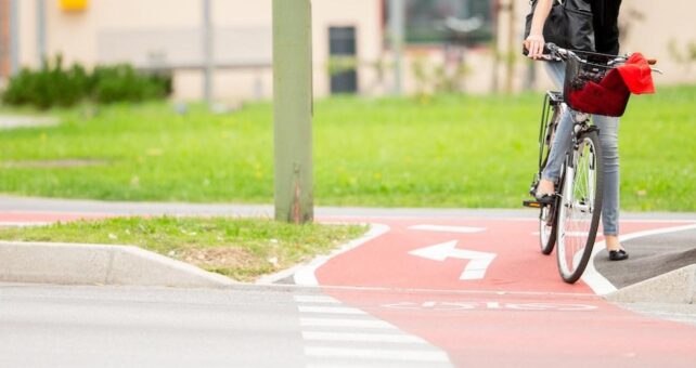 Young Woman on Bicycle Waiting at crosswalk - Photo courtesy Getty Images