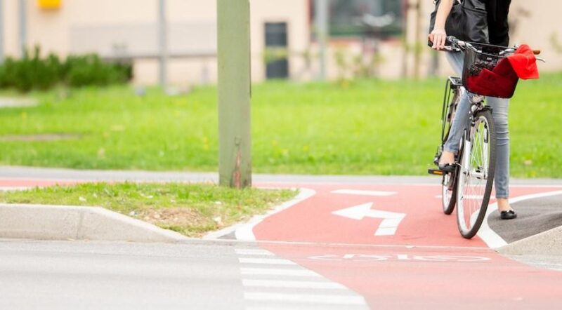 Young Woman on Bicycle Waiting at crosswalk - Photo courtesy Getty Images