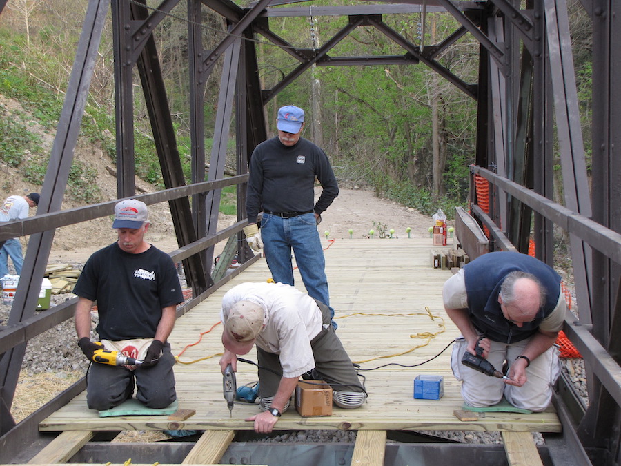 Volunteers installing decking on a small Montour Trail bridge in South Park Township