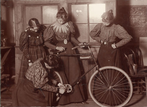 “Women Repairing Bicycle, c. 1895” by Unknown – http-::arc.lib.montana.edu:msu-photos:item:135. Licensed under CC BY-SA 3.0 via Wikimedia Commons.