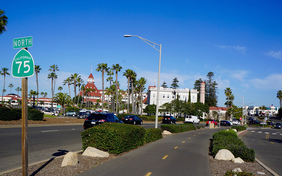 As the Bayshore Bikeway passes by the historic Hotel del Coronado (on the left), it transitions to a separated path in the middle of the traffic lanes along CA 75/Silver Strand Boulevard. | Photo by Cindy Barks