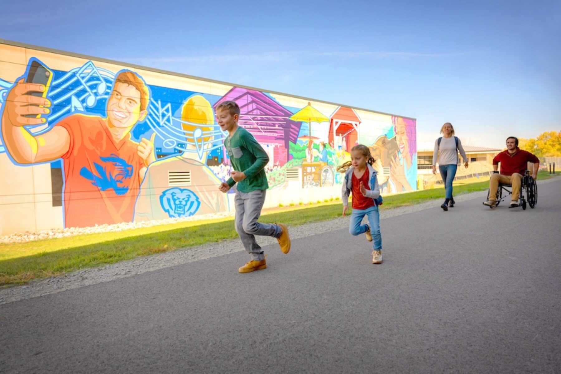 Walkers and wheelchair user along a mural along Indiana's Nickel Plate Trail in Fishers | Photo courtesy Hamilton County Tourism