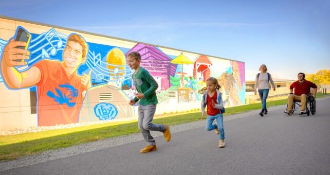 Walkers and wheelchair user along a mural along Indiana's Nickel Plate Trail in Fishers | Photo courtesy Hamilton County Tourism