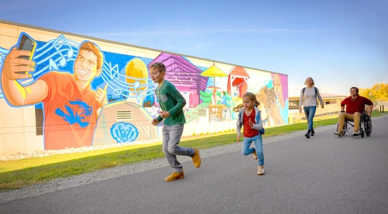 Walkers and wheelchair user along a mural along Indiana's Nickel Plate Trail in Fishers | Photo courtesy Hamilton County Tourism