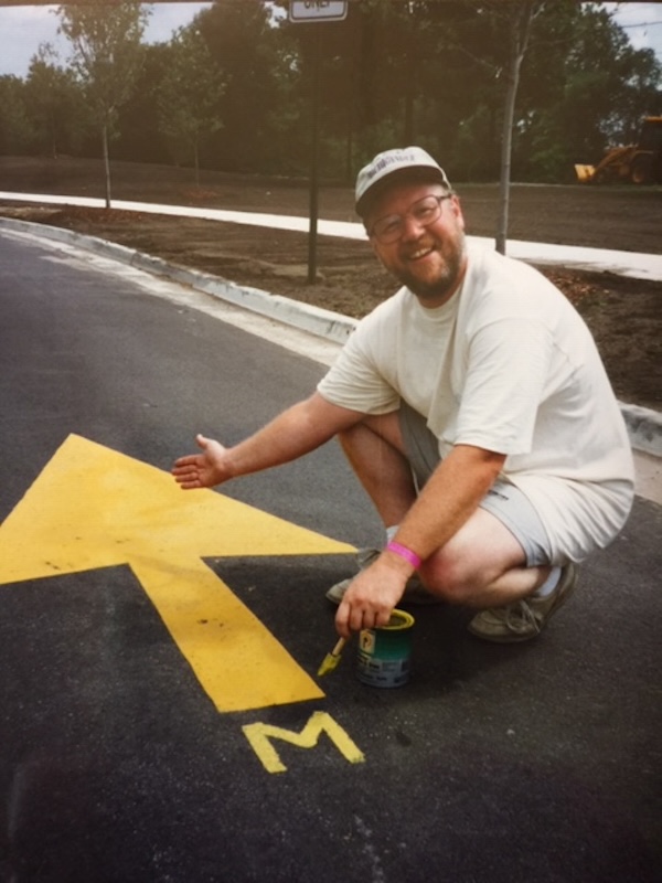The first director of RTC’s Michigan field office, Roger Storm, painting wayfinding signage for the signature Michigander bike ride across the state (circa 1995) | Photo courtesy Roger Storm